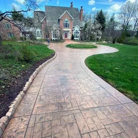 Stamped concrete overlay driveway, earth-tone stain, brick home
